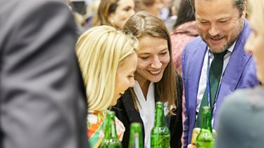 Three people are smiling while enjoying drinks at WTCE