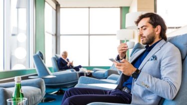 man taking cup of tea while looking on his phone